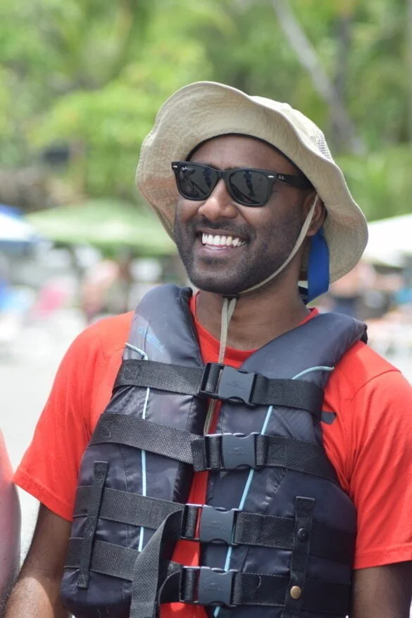 Posing before parasailing, wearing sunglasses and a secure hat