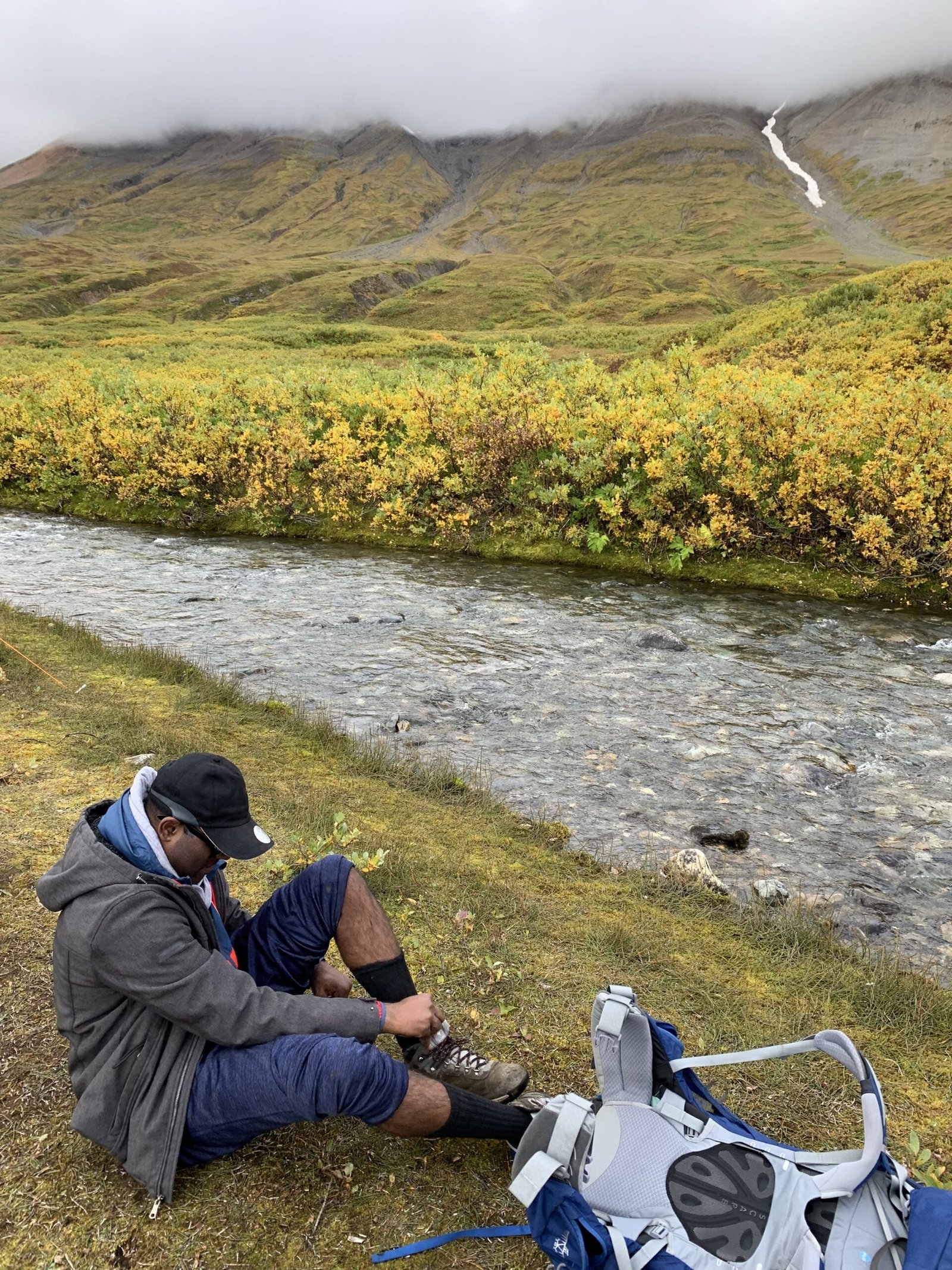 Arujan putting his shoes back on after crossing the creek